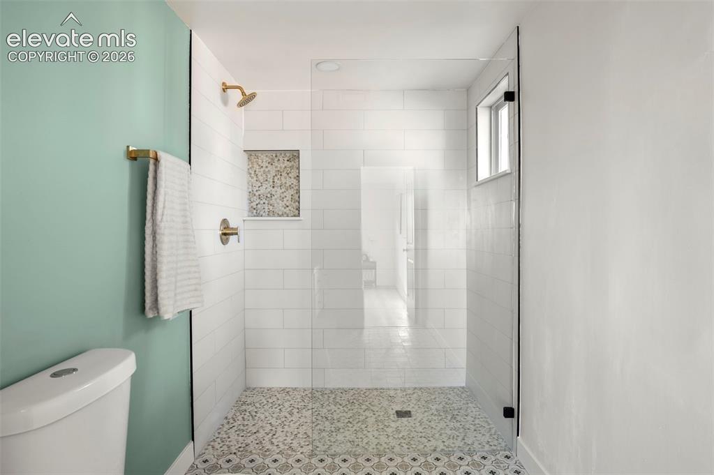 Image 29 of 50: Walk-in shower featuring a glass enclosure, subway tile walls, patterned fl