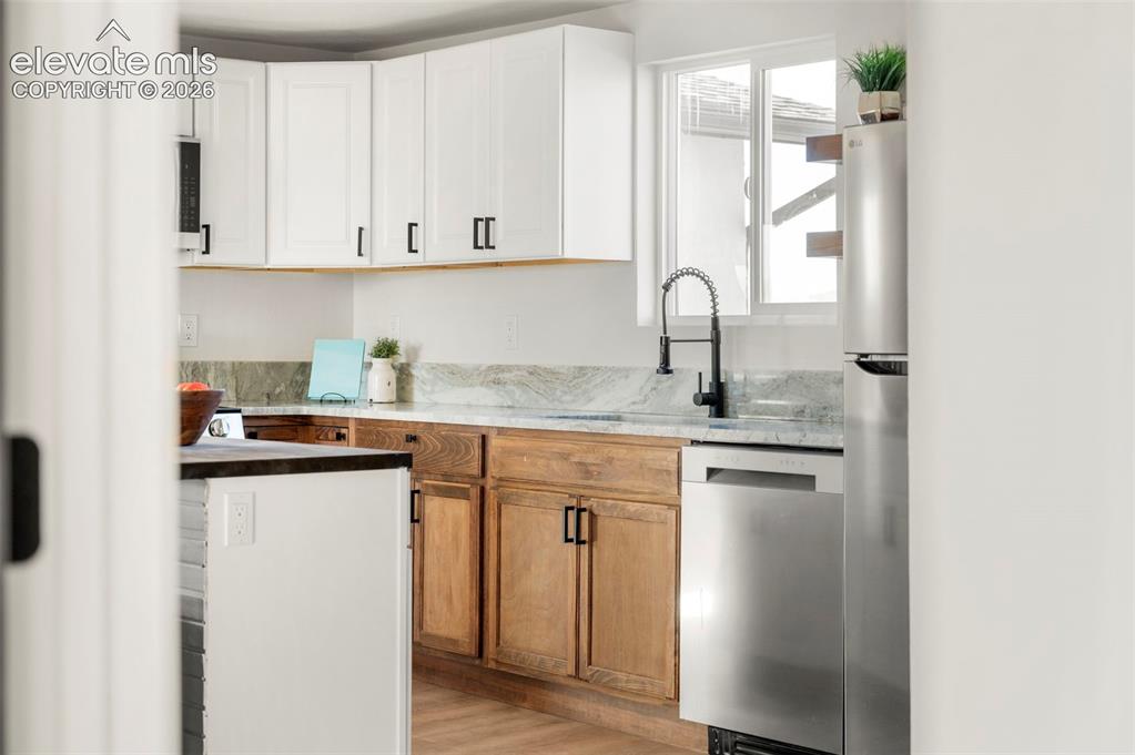 Image 44 of 50: Kitchen featuring two-tone cabinetry with white upper and wood-finish lower