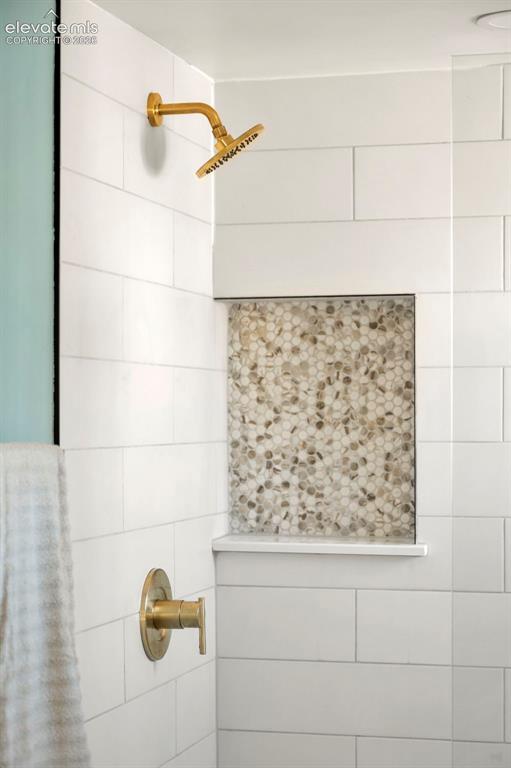 Image 46 of 50: Shower with subway tile surround, brass fixtures, and a recessed niche feat