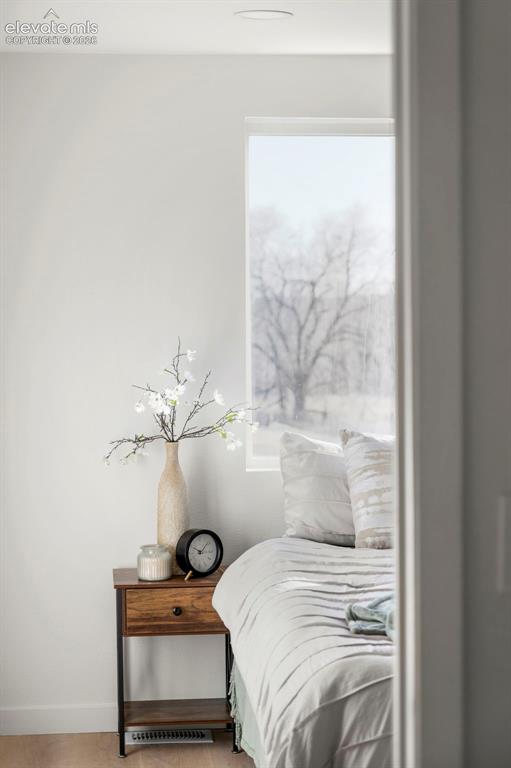Image 47 of 50: Bright bedroom featuring a large window, recessed lighting, and wood-finish