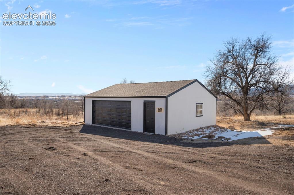 Image 48 of 50: Detached garage structure featuring a two-car garage door, a single entry d