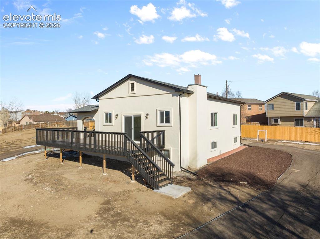 Image 5 of 50: Rear exterior with a spacious elevated deck featuring dark railings and sta