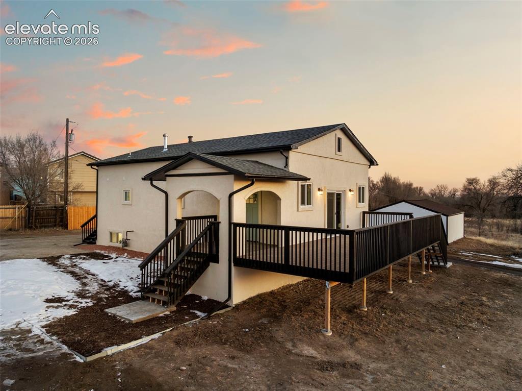 Image 6 of 50: Rear exterior featuring a spacious elevated deck with dark railings, a whit