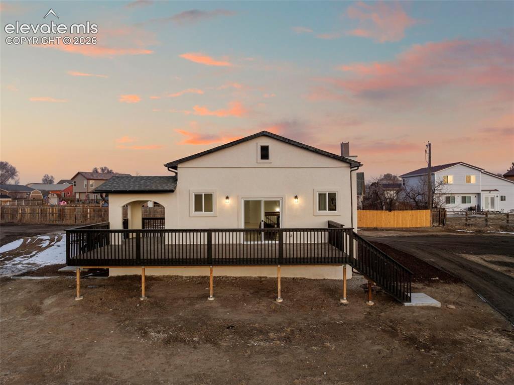 Image 7 of 50: Exterior of a stucco residence featuring a dark shingle roof and an expansi