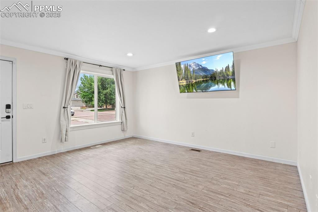 Image 12 of 39: Spare room with ornamental molding, wood finished floors, and recessed ligh