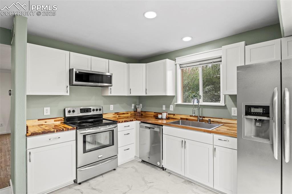 Image 14 of 39: Kitchen with butcher block counters, appliances with stainless steel finish