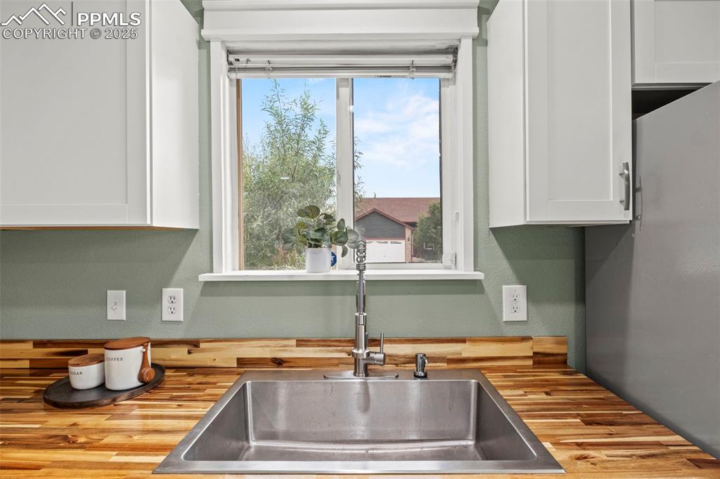 Image 16 of 39: Kitchen with wood counters and white cabinets