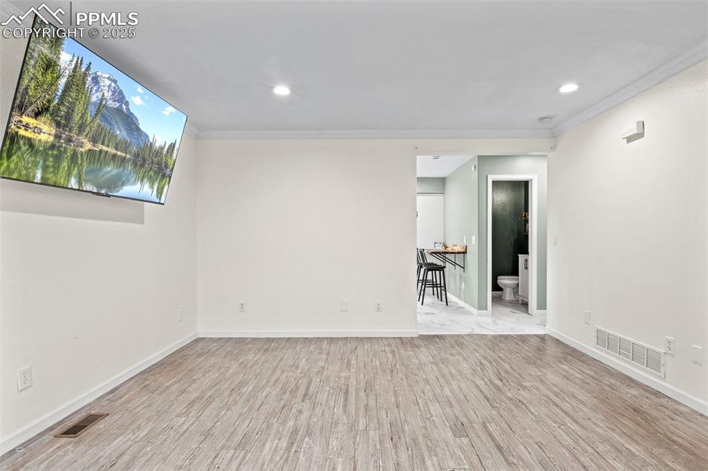 Image 8 of 39: Empty room featuring wood finished floors, crown molding, and recessed ligh