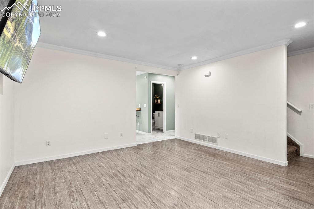 Image 9 of 39: Unfurnished room with crown molding, wood finished floors, recessed lightin