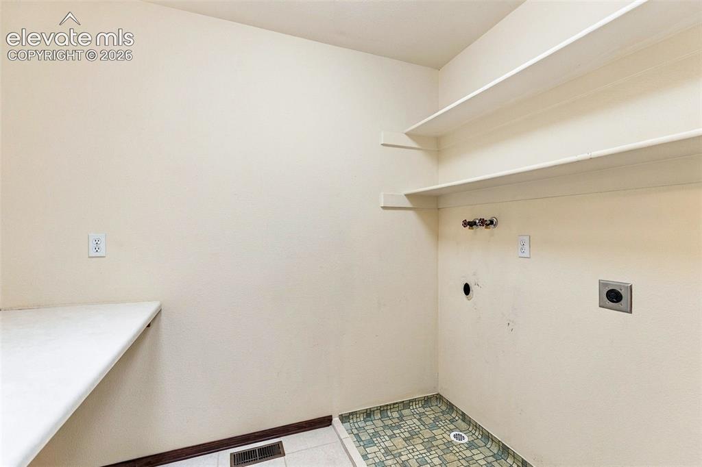 Image 27 of 49: Upper level laundry with folding table and room for cabinets.