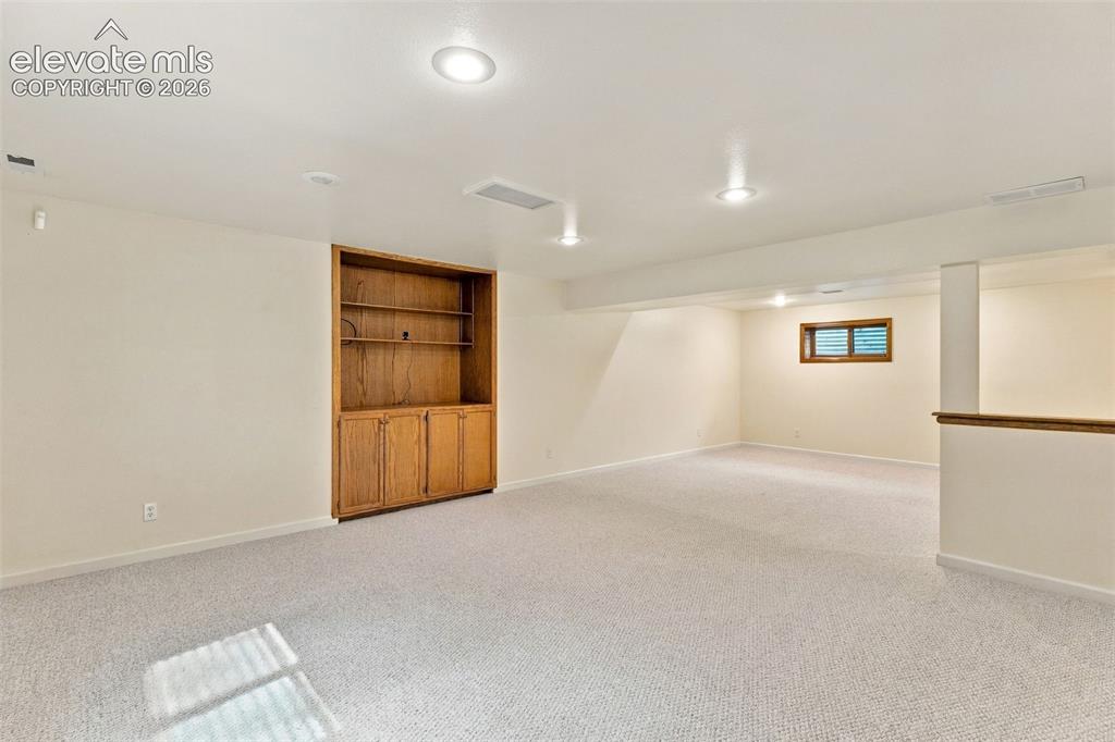 Image 31 of 49: Basement rec room with built-ins.