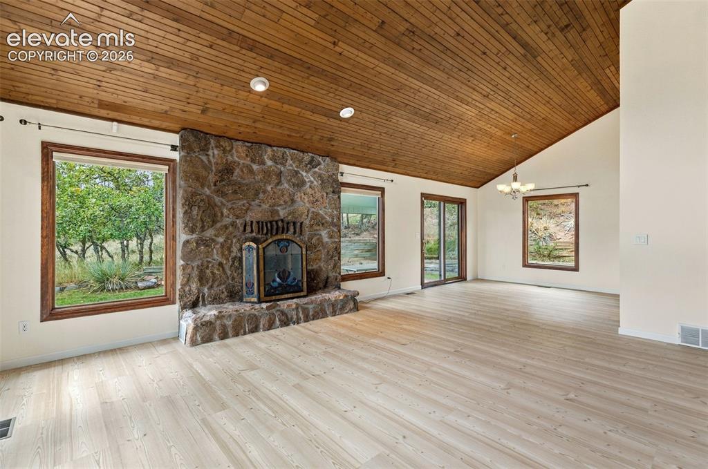 Image 7 of 49: Main level living room with newer LVP flooring and wood buring fireplace.