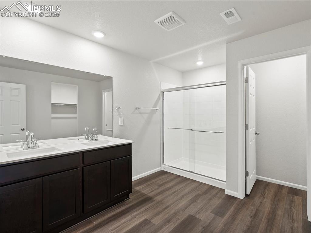 Image 16 of 25: Bathroom featuring dark wood-type flooring, a stall shower, double vanity,