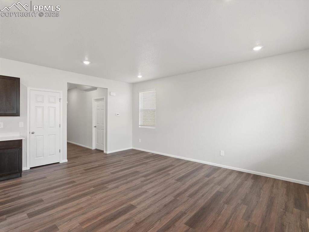 Image 3 of 25: Unfurnished living room featuring dark wood-style flooring and recessed lig