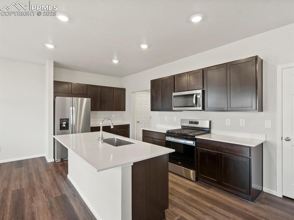 Image 5 of 25: Kitchen with appliances with stainless steel finishes, dark brown cabinets,