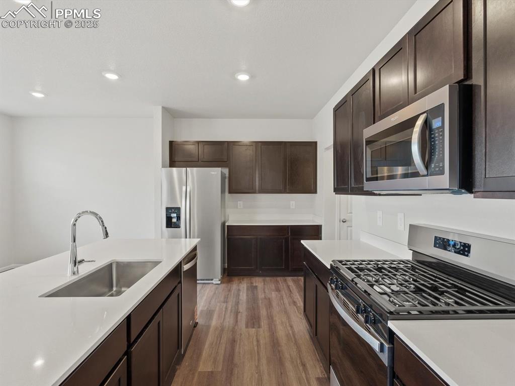 Image 6 of 25: Kitchen featuring stainless steel appliances, dark brown cabinetry, light w