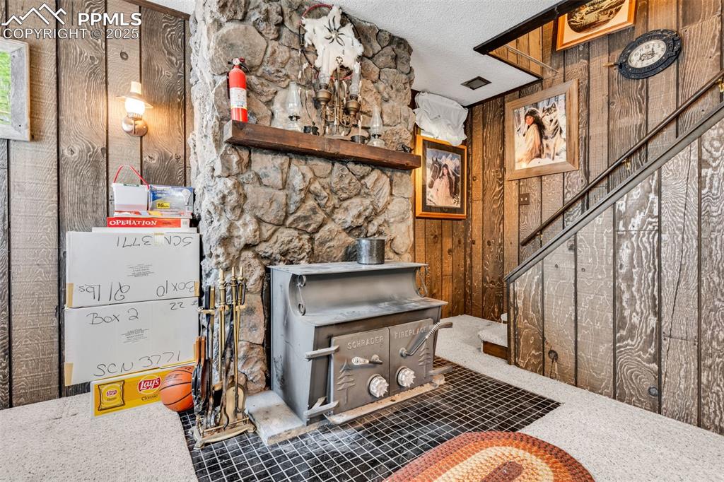 Image 13 of 33: Living area featuring wood walls, stairs, and a textured ceiling