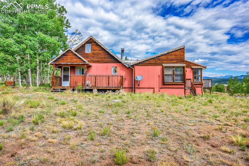 Image 2 of 33: Rear view of property featuring a wooden deck
