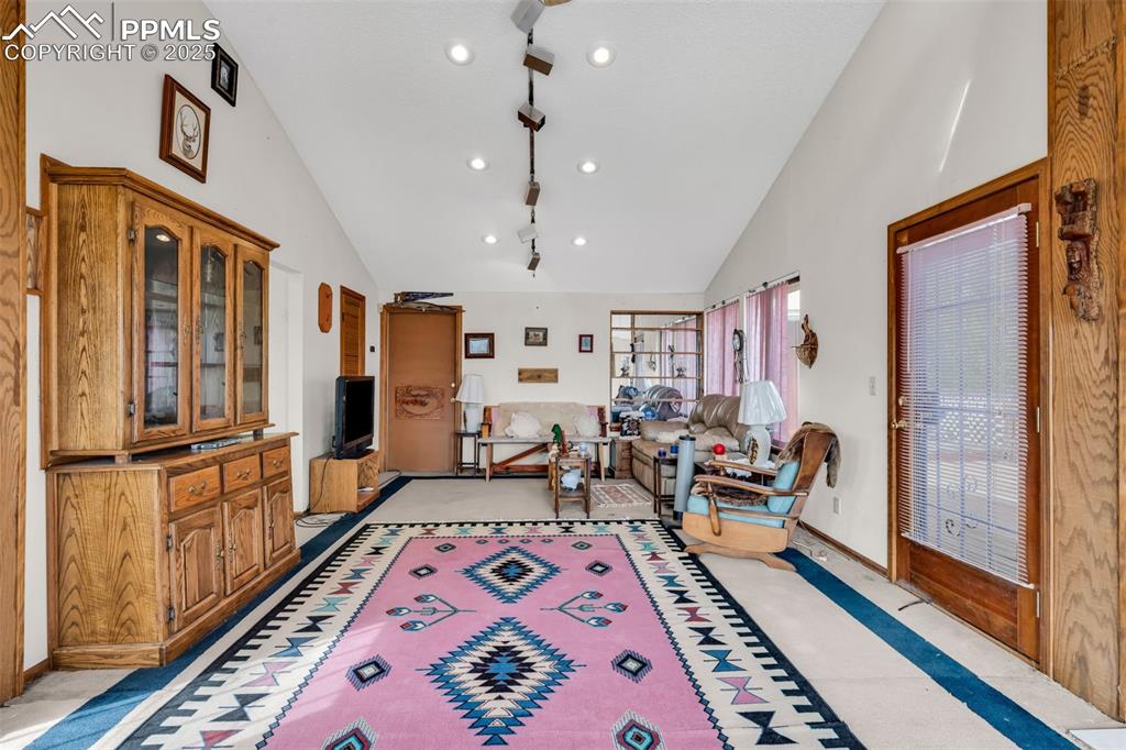 Image 20 of 33: Living area with high vaulted ceiling and baseboards