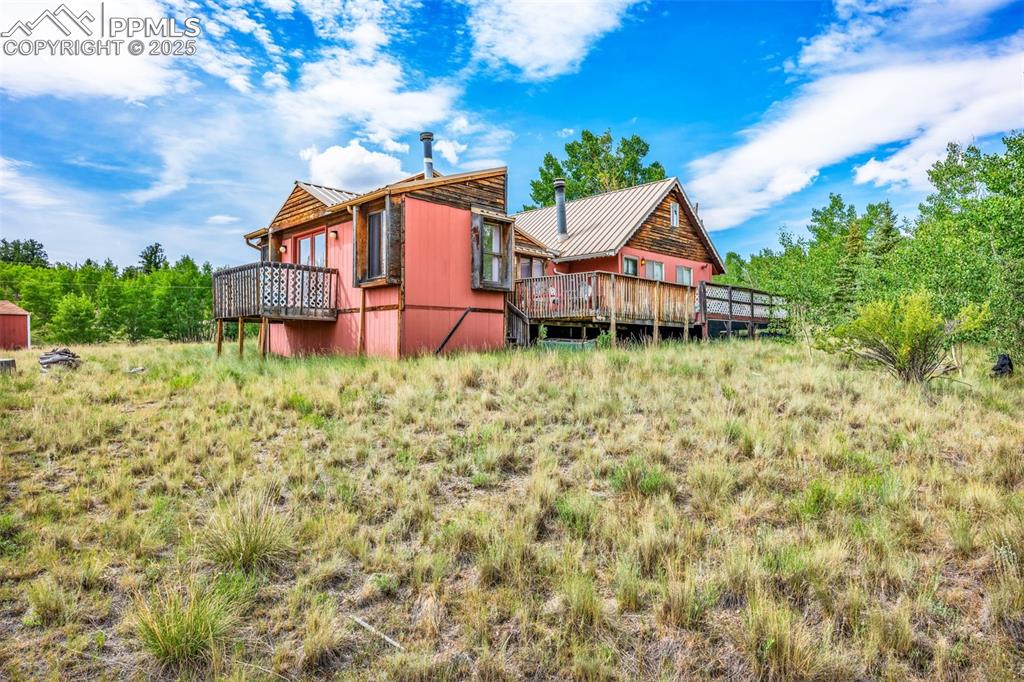 Image 25 of 33: Rear view of property with a metal roof and a wooden deck