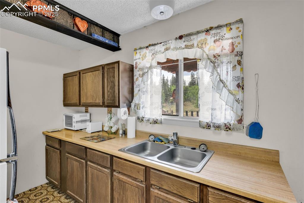 Image 7 of 33: Kitchen featuring light countertops, a textured ceiling, and freestanding r