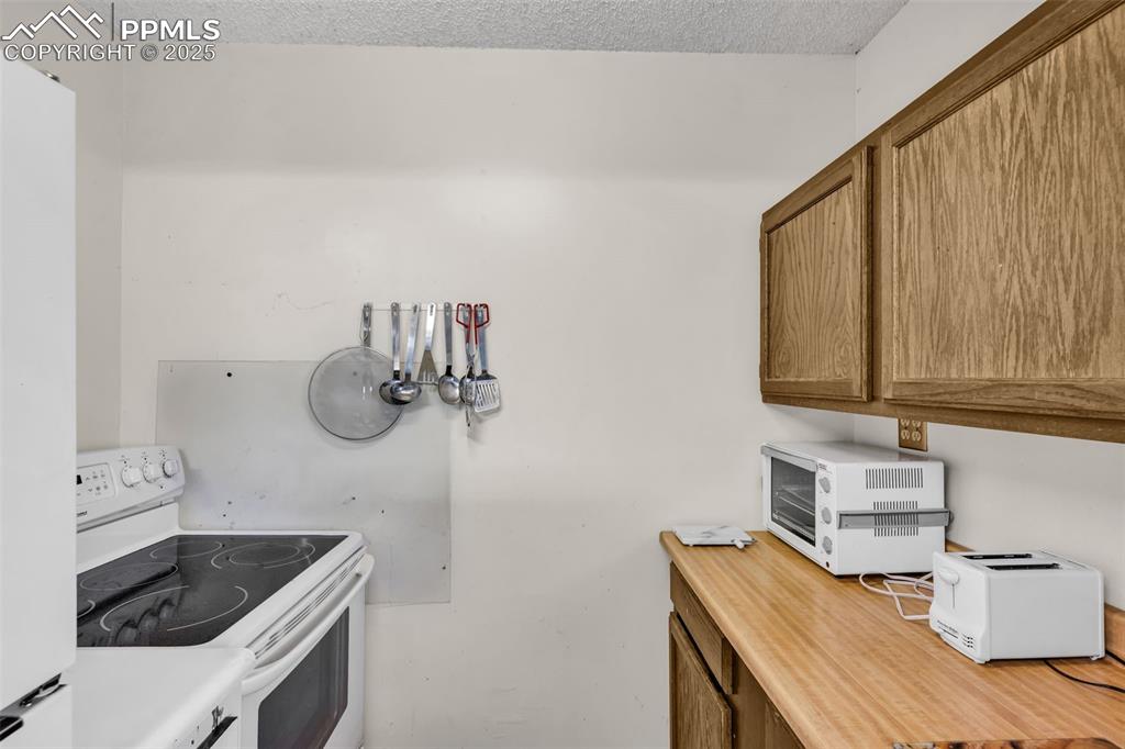 Image 8 of 33: Kitchen featuring white appliances, a textured ceiling, an office area, and
