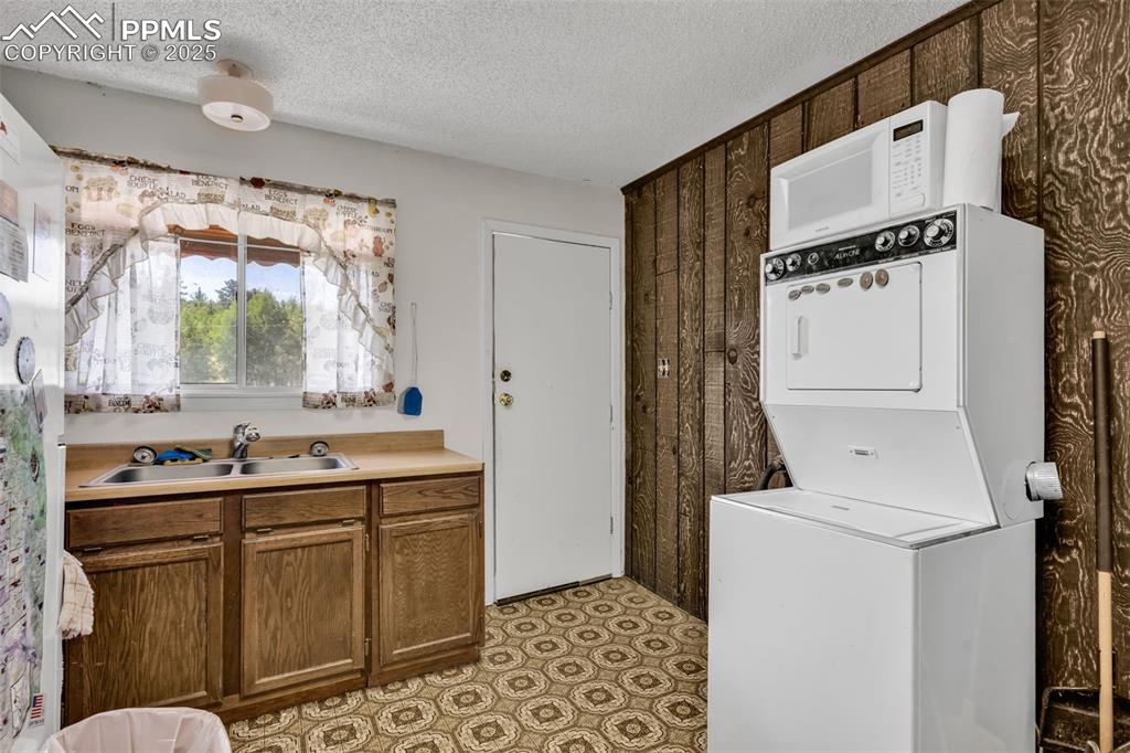 Image 9 of 33: Washroom featuring stacked washer and clothes dryer and a textured ceiling