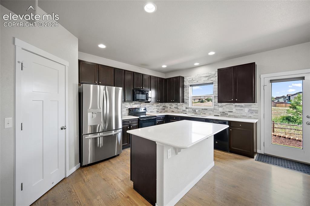 Image 3 of 48: Beautiful kitchen with stone backsplash and quartz countertops.