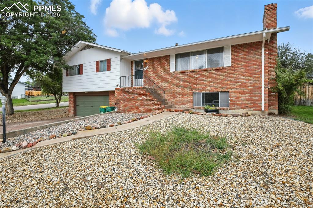 Image 7 of 35: View of front of property with brick siding, a garage, a chimney, and drive