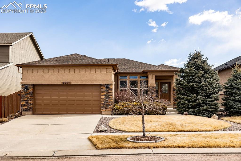 Image 1 of 49: Prairie-style house featuring stone siding, an attached garage, concrete dr
