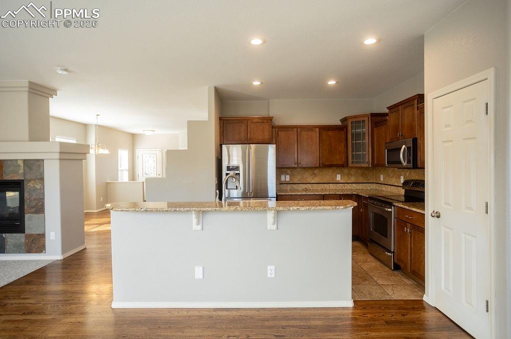 Image 10 of 49: Kitchen with stainless steel appliances, glass insert cabinets, light stone