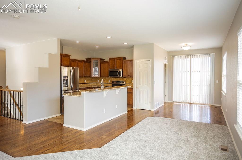 Image 7 of 49: Kitchen featuring dark wood-type flooring, light stone countertops, stainle