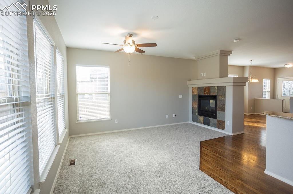 Image 8 of 49: Unfurnished living room featuring carpet, a tiled fireplace, ceiling fan, a