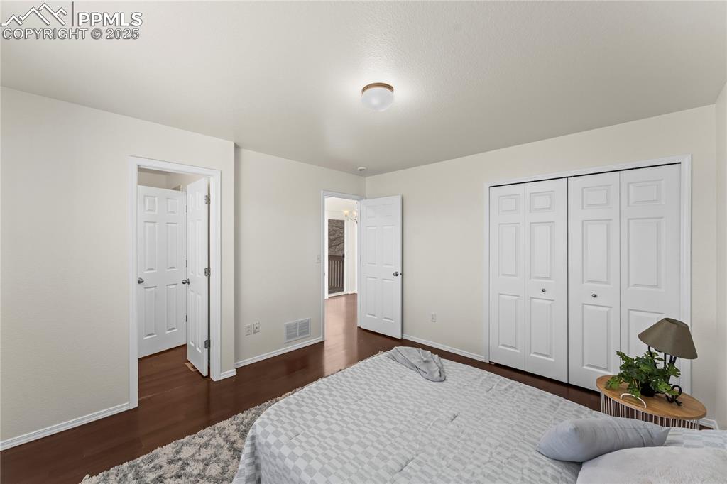 Image 13 of 22: Primary bedroom with large closet space and door to bathroom.