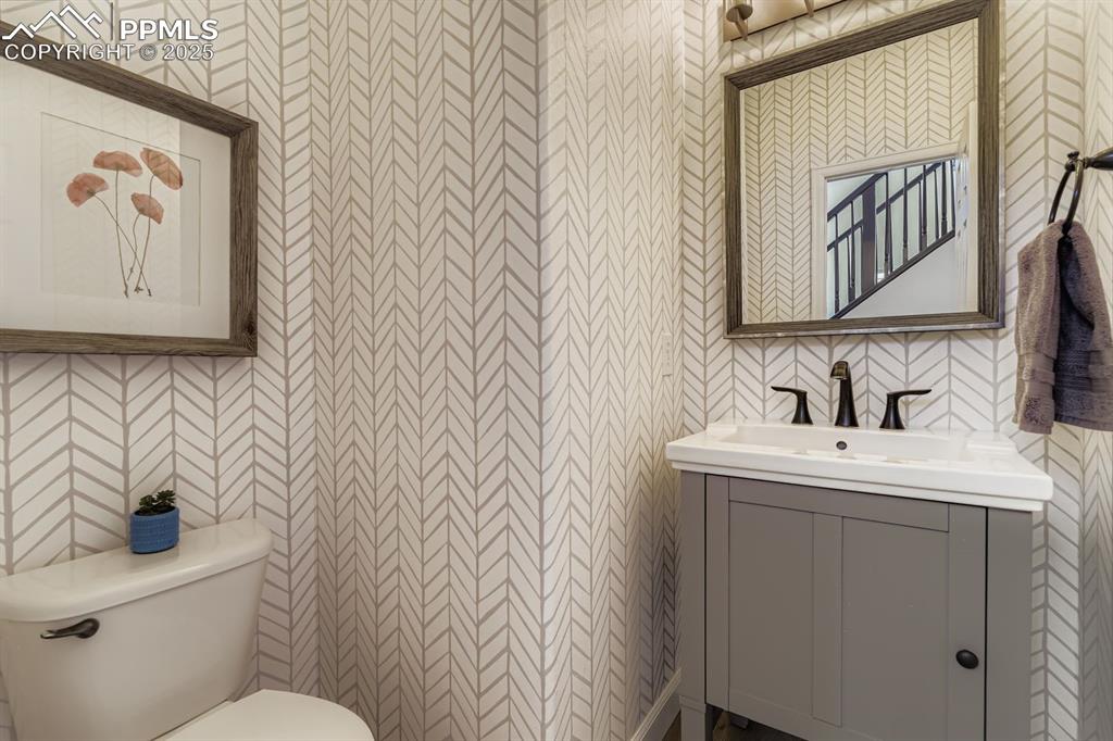 Image 10 of 32: Half bath with vanity and wallpapered walls