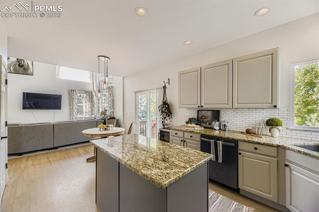 Image 13 of 32: Kitchen featuring gray cabinets, light stone counters, tasteful backsplash,