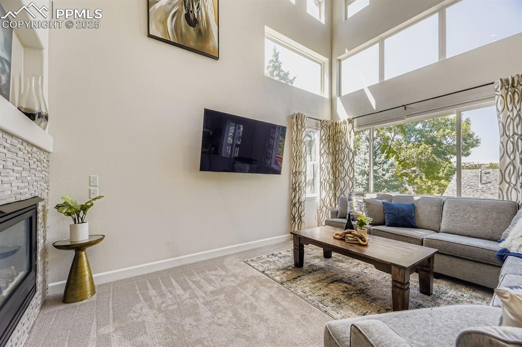 Image 14 of 32: Carpeted living area featuring a fireplace and a high ceiling