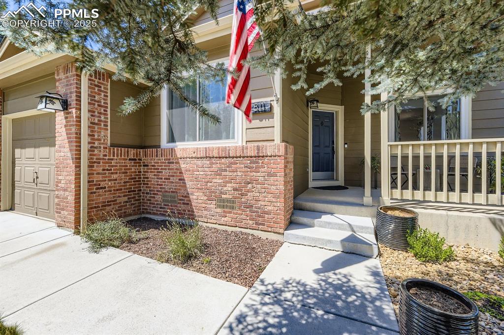 Image 2 of 32: Doorway to property with an attached garage and brick siding
