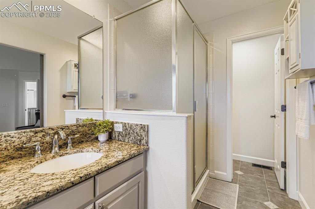 Image 22 of 32: Full bath with a shower stall, vanity, and light tile patterned floors