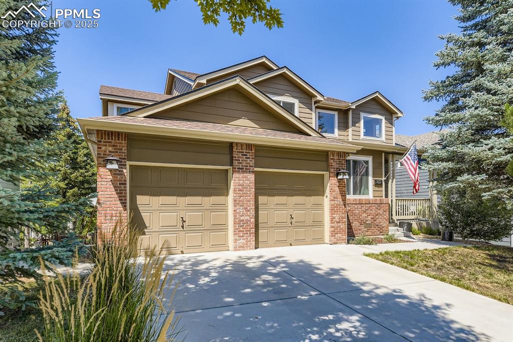 Image 27 of 32: View of front facade featuring brick siding, a shingled roof, a garage, and