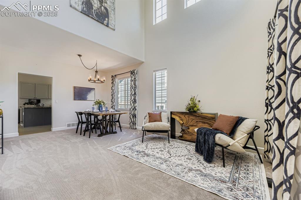 Image 5 of 32: Sitting room featuring light carpet, a towering ceiling, and a chandelier