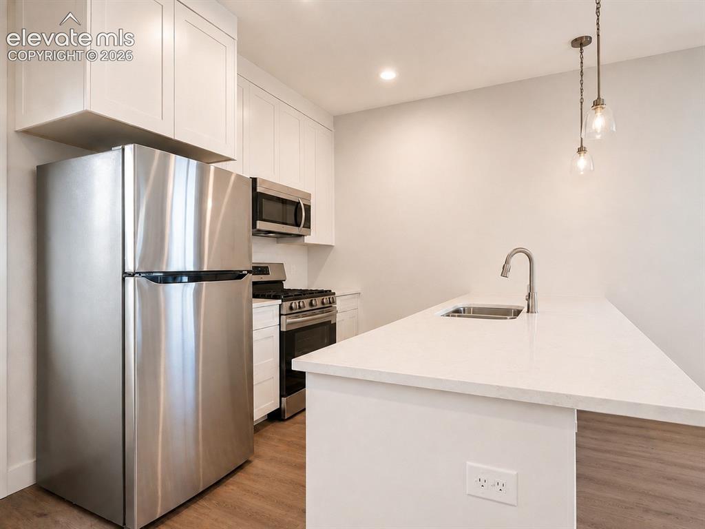 Image 7 of 19: Kitchen featuring stainless steel appliances, white cabinetry, wood-finish 