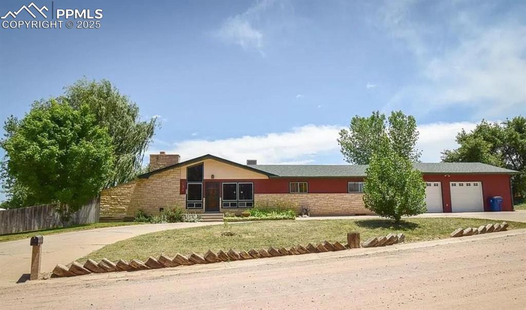 Image 2 of 23: View of front of home with an attached garage, driveway, fence, and a chimn