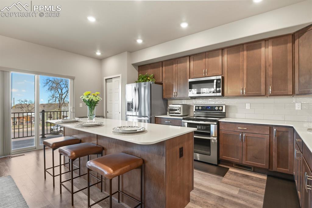 Image 10 of 33: Spacious kitchen featuring wood-finish flooring, ample cabinetry with stain