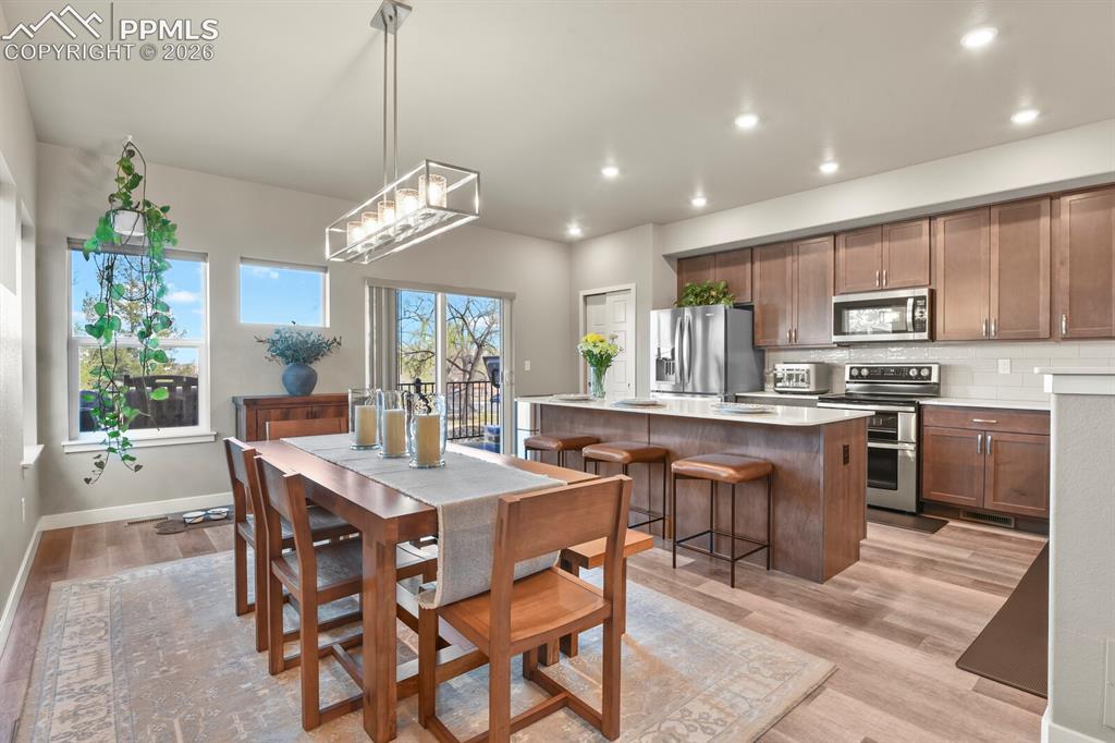 Image 14 of 33: Open-concept kitchen and dining area featuring wood-finish flooring, recess
