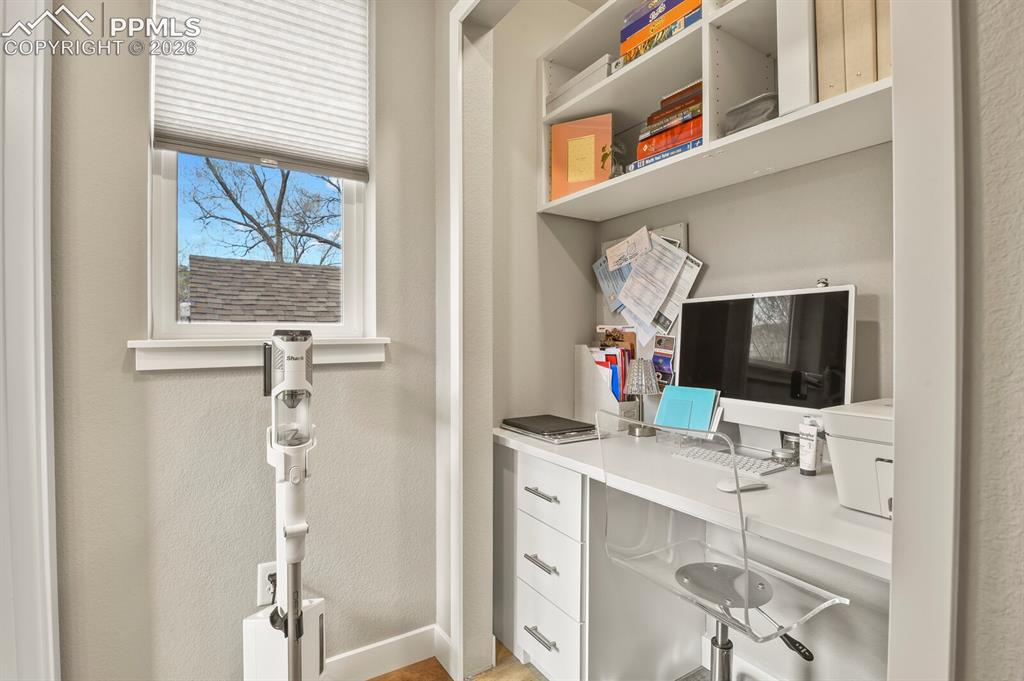 Image 15 of 33: Dedicated workspace featuring a built-in desk, shelving, and drawer storage