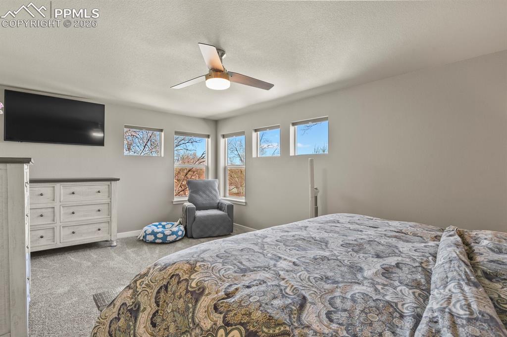 Image 20 of 33: Spacious room featuring light gray wall paint, textured carpeting, and a ce