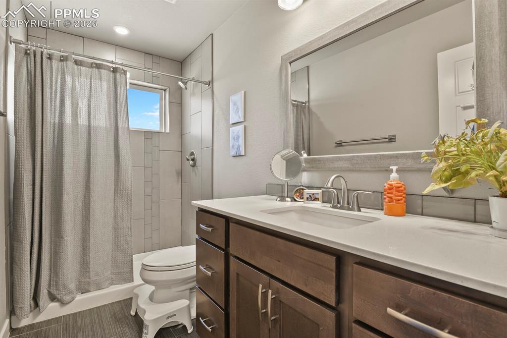 Image 27 of 33: Contemporary bathroom featuring a dark wood-finish vanity with ample storag