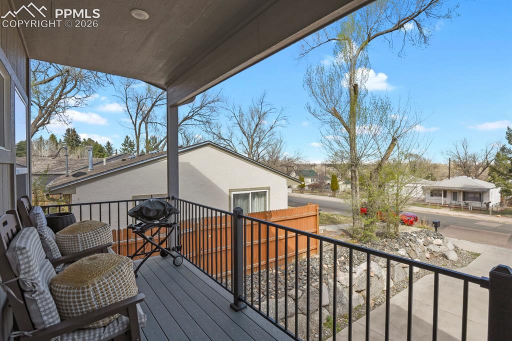 Image 29 of 33: Covered deck featuring composite decking, black metal railings, recessed li