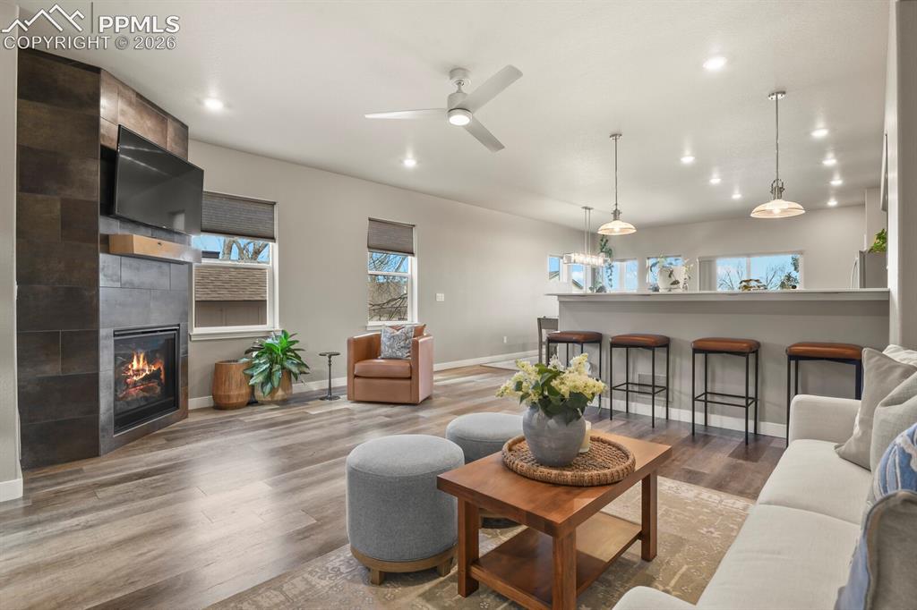 Image 7 of 33: Living area featuring a floor-to-ceiling tiled fireplace, wood-finish floor